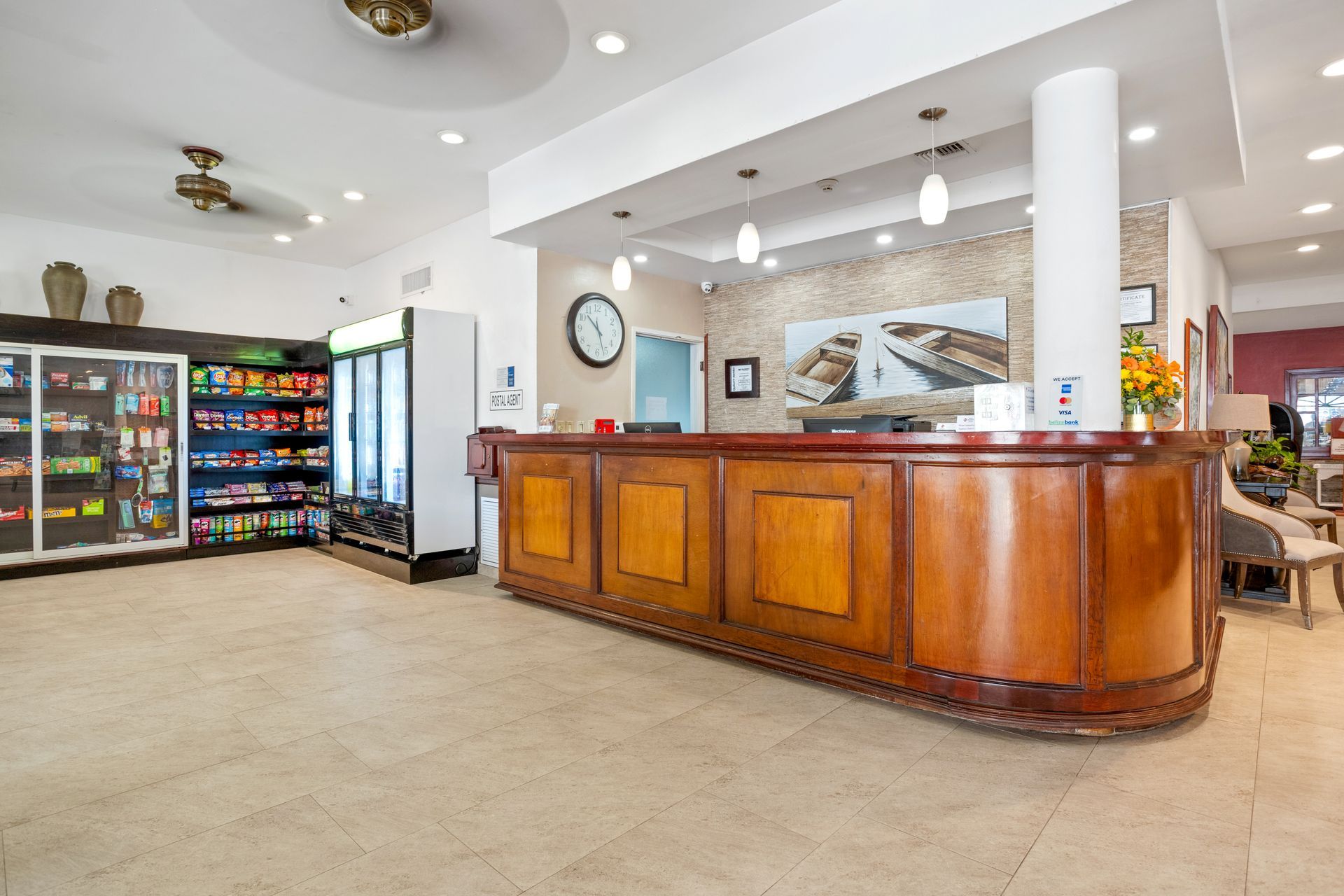 A hotel lobby with a wooden counter and a clock on the wall.
