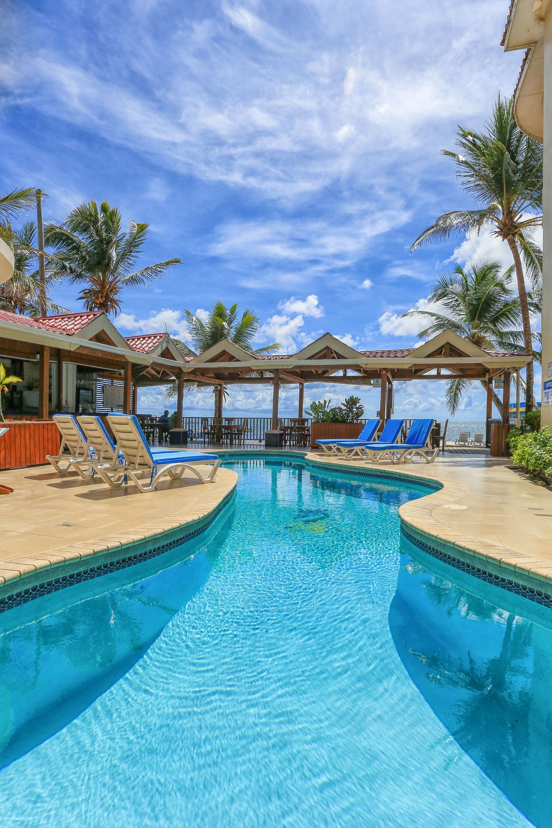 A large swimming pool surrounded by chairs and umbrellas on a sunny day.