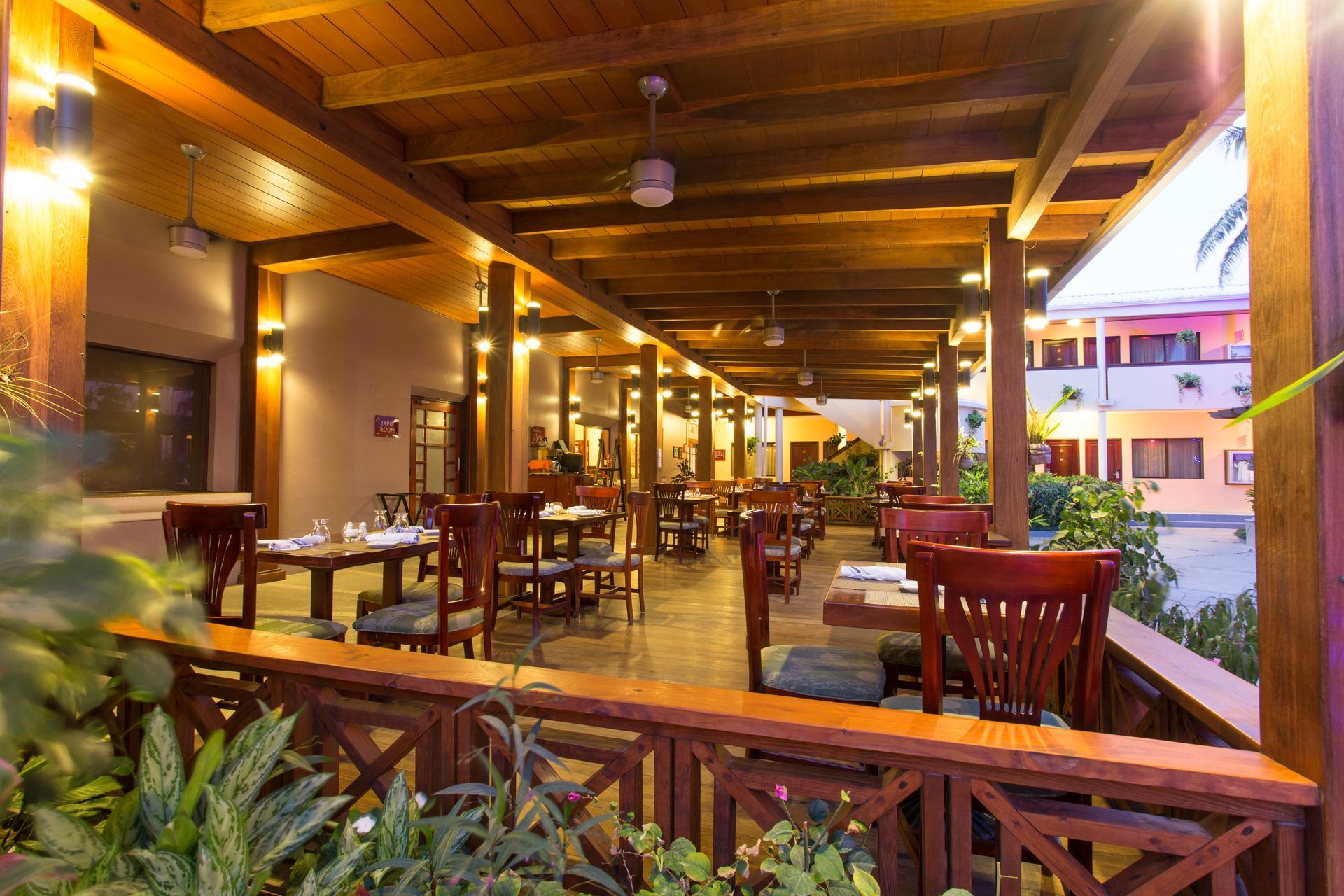 a restaurant with tables and chairs under a wooden roof .