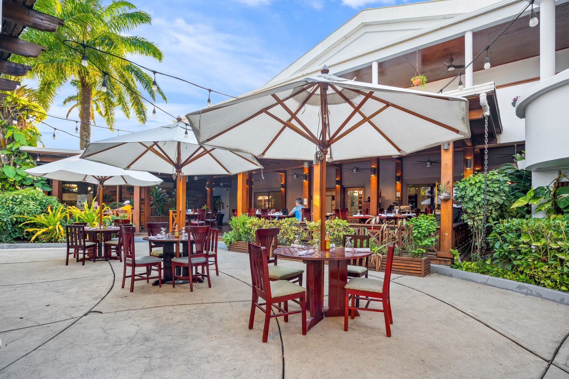 Tables and chairs under umbrellas outside of a restaurant