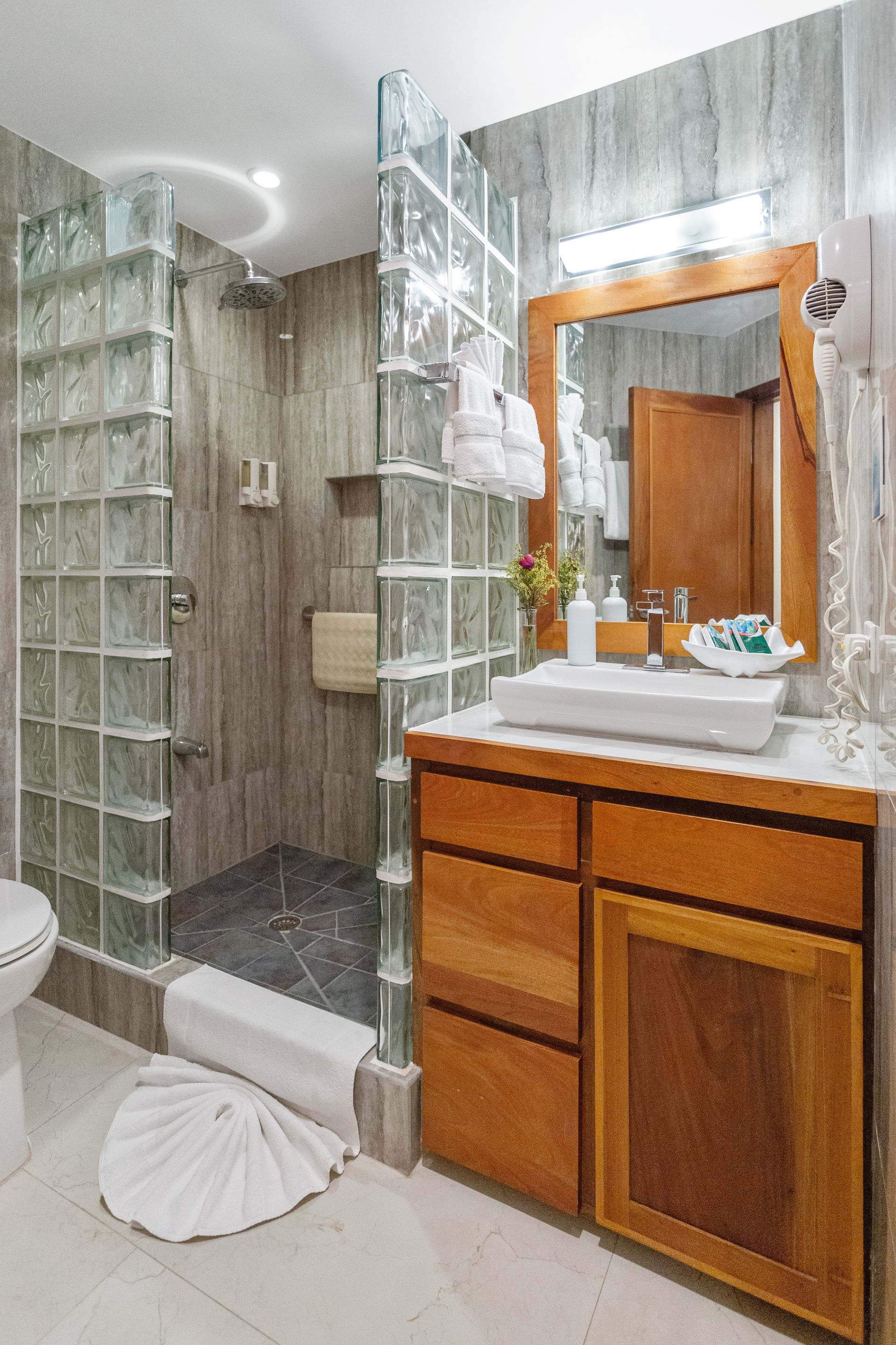 A bathroom with a sink , toilet , shower and mirror.