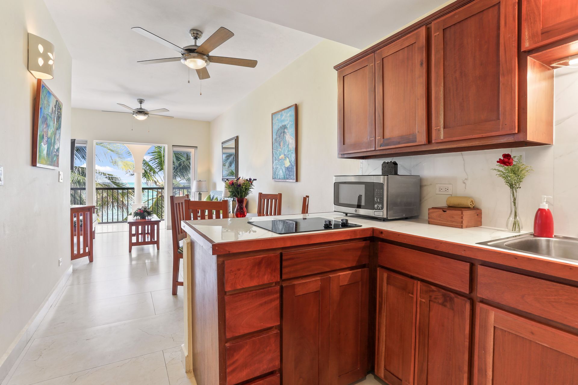 A kitchen with wooden cabinets , a sink , a microwave , and a ceiling fan.
