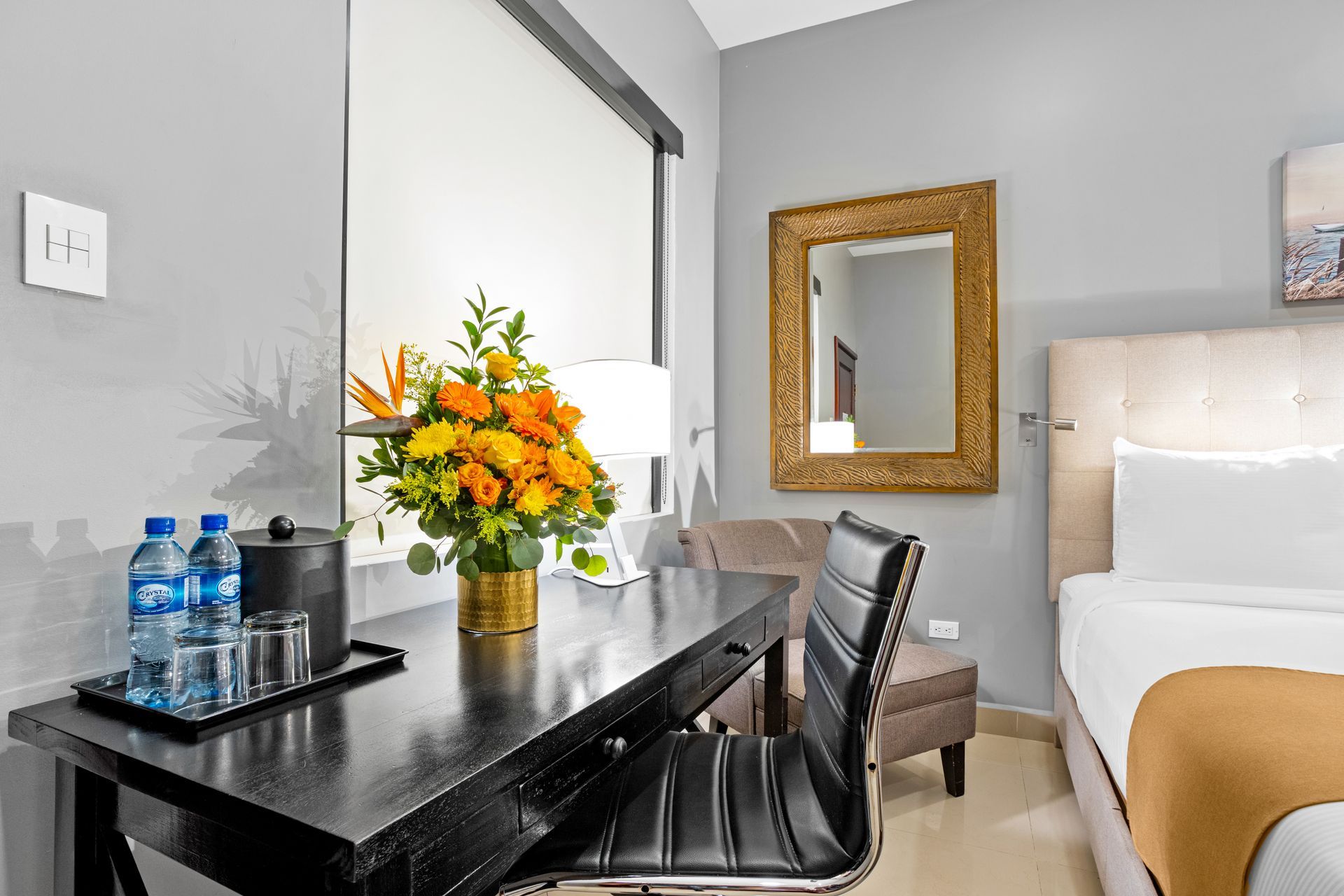 a hotel room with a desk , chair , bed and mirror .