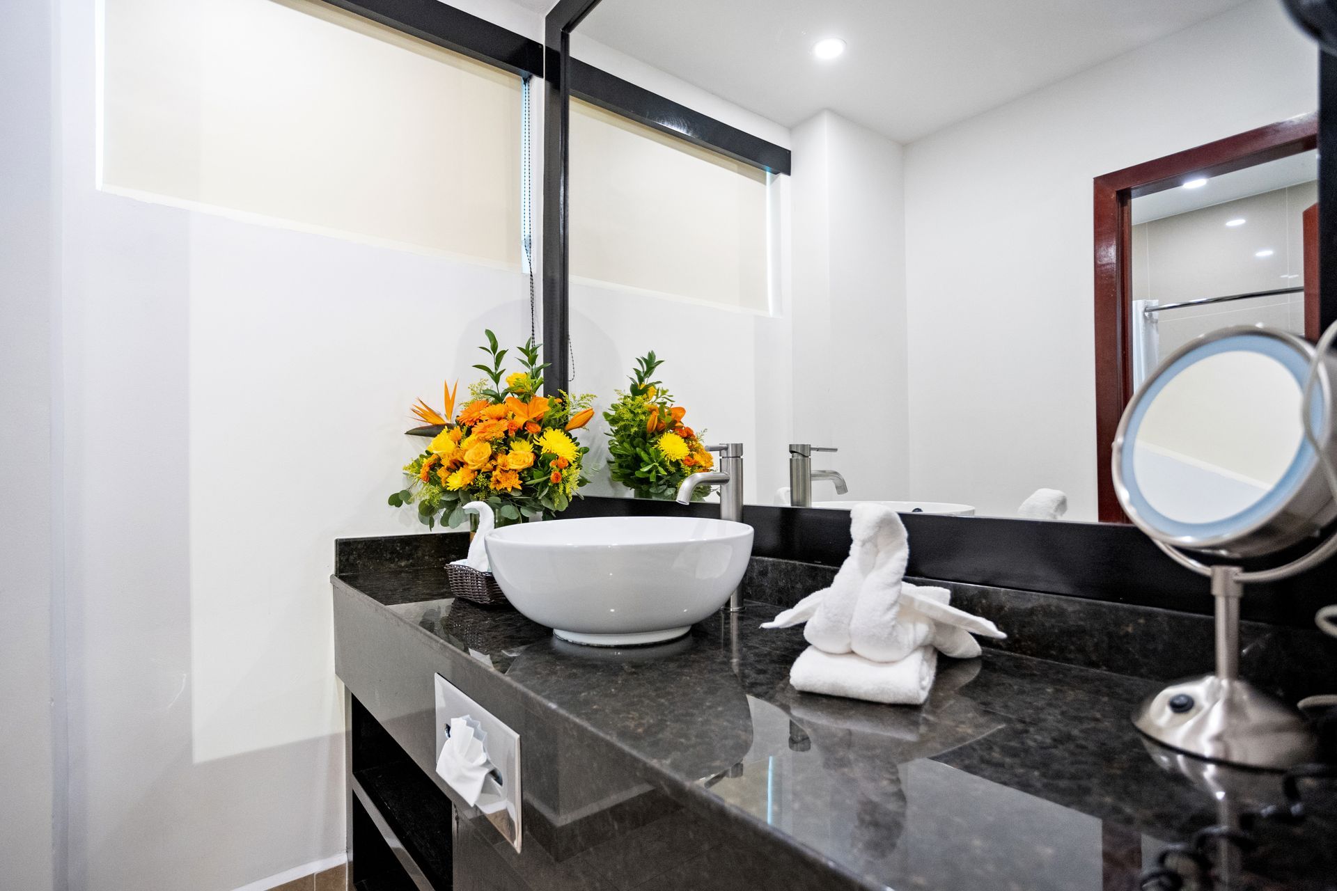 A bathroom with a sink , mirror and flowers on the counter.