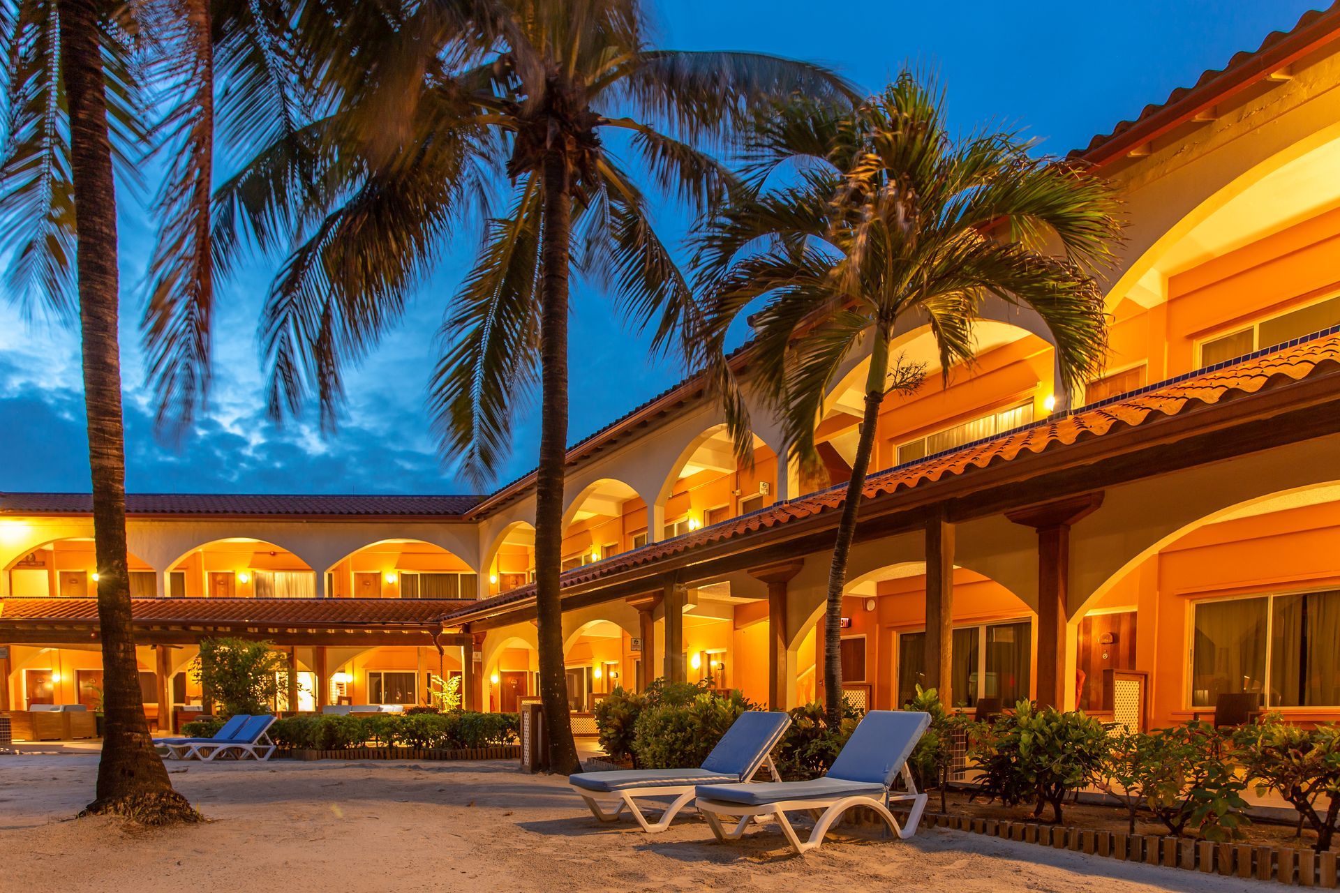 a hotel with palm trees and chairs in front of it