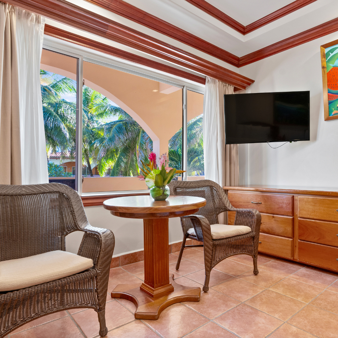 A living room with a table and chairs and a flat screen tv