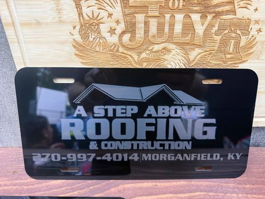 Black and gray roofing company sign reading “A Step Above Roofing & Construction” with phone number.