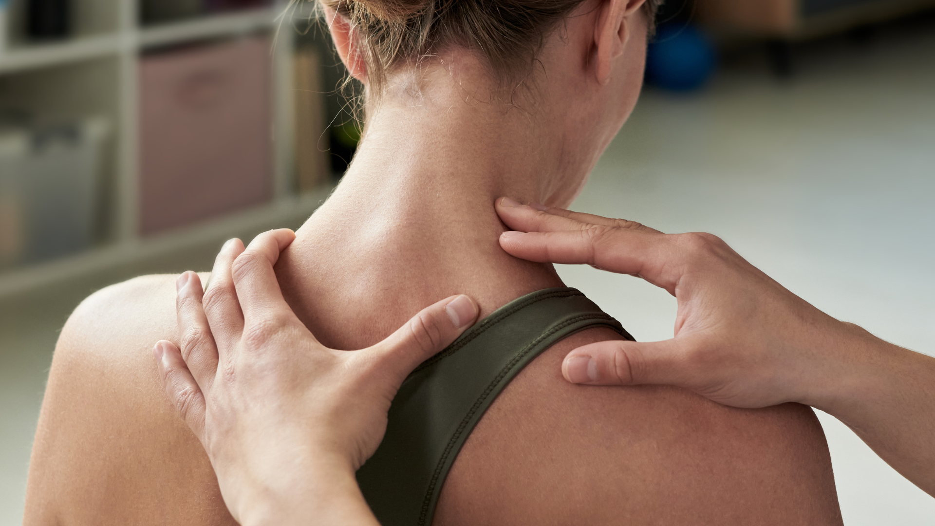 Hands pressing a person’s neck and shoulder during a massage or pain relief treatment