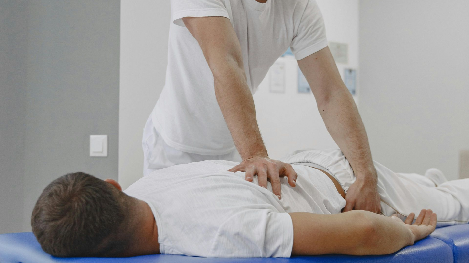 Physical therapist doing a back adjustment on a patient lying face down on a treatment table