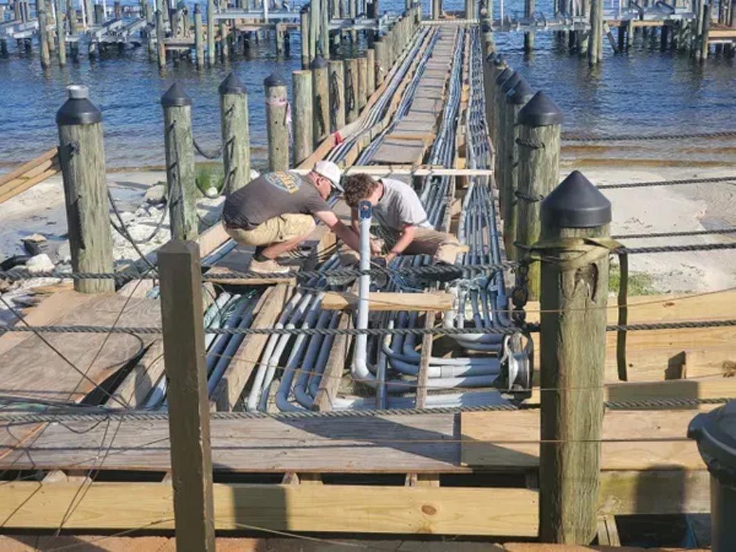 A group of men are working on a dock overlooking the water.
