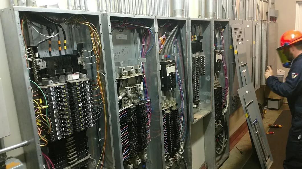 A man is working on a electrical panel in a room.