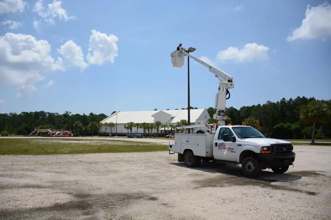 A white truck with a crane on top of it is parked in a parking lot.