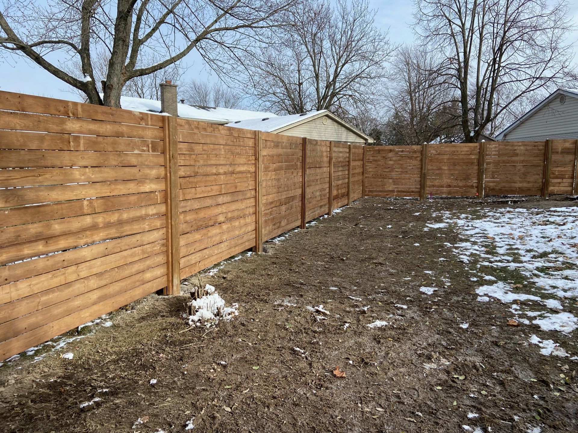 A wooden fence is in the backyard of a house.