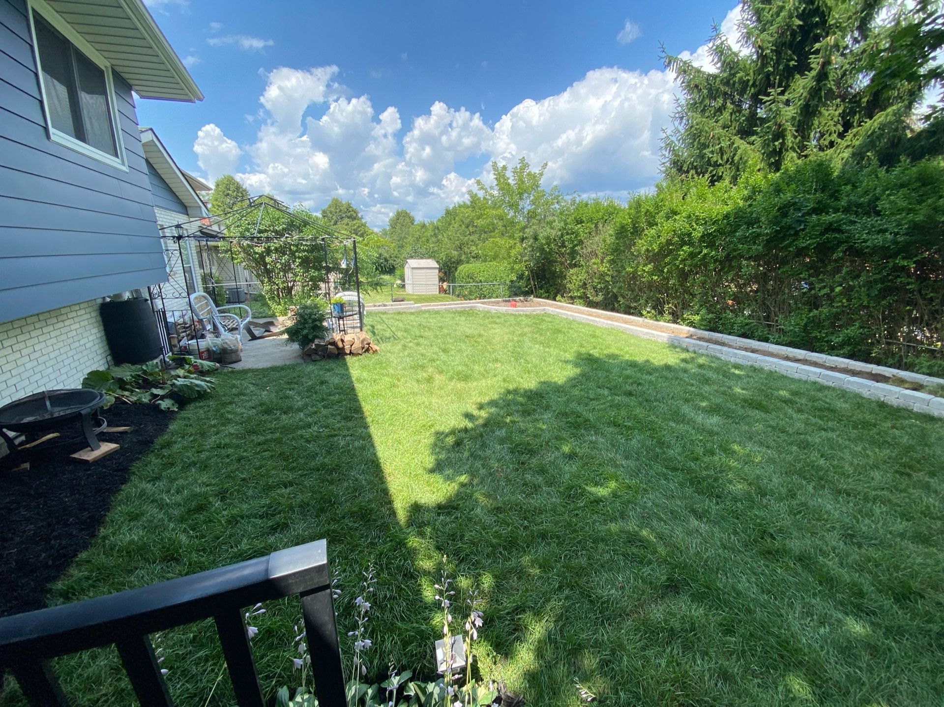 A backyard with a lush green lawn and a house in the background.