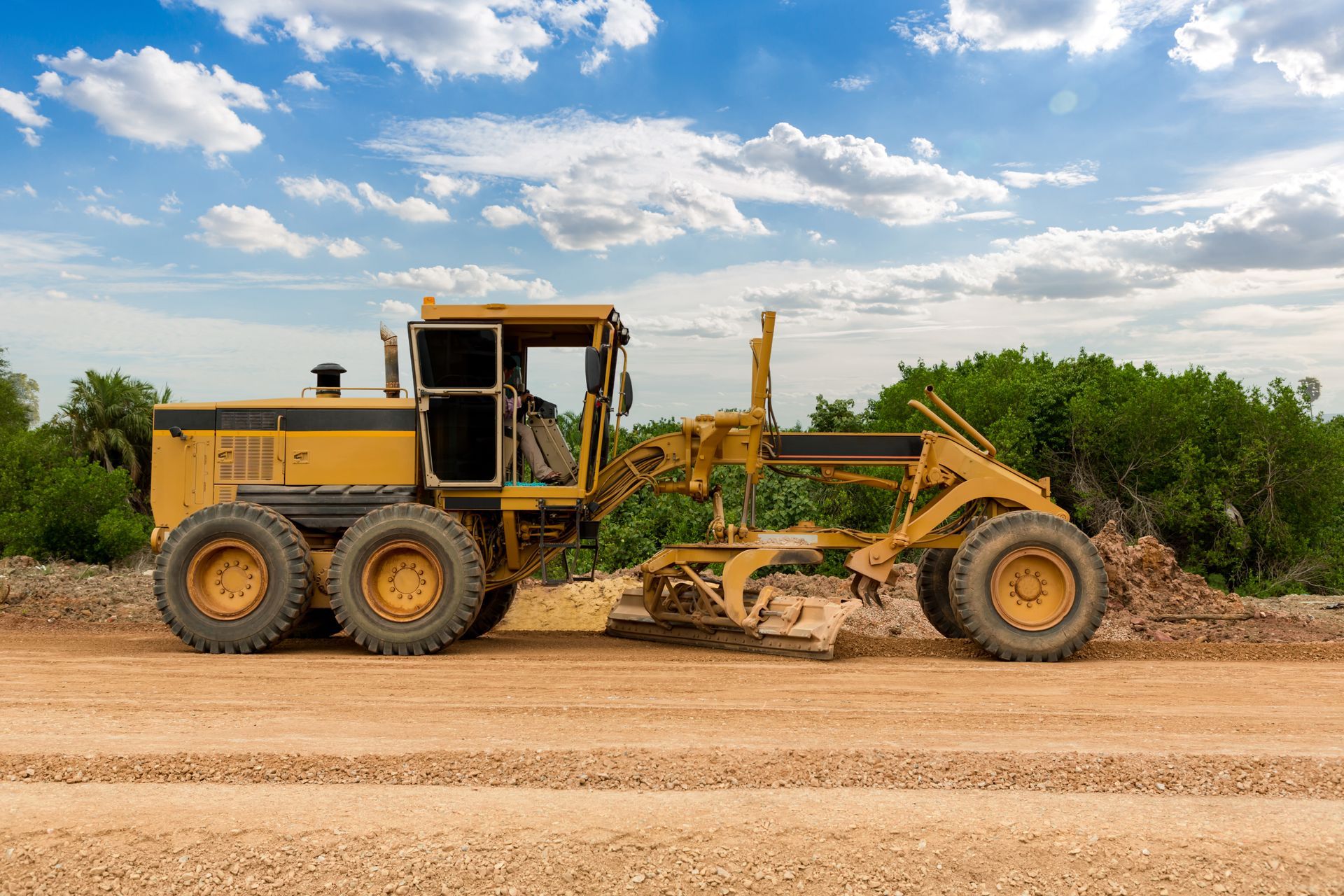 A yellow bulldozer is moving dirt on a dirt road.