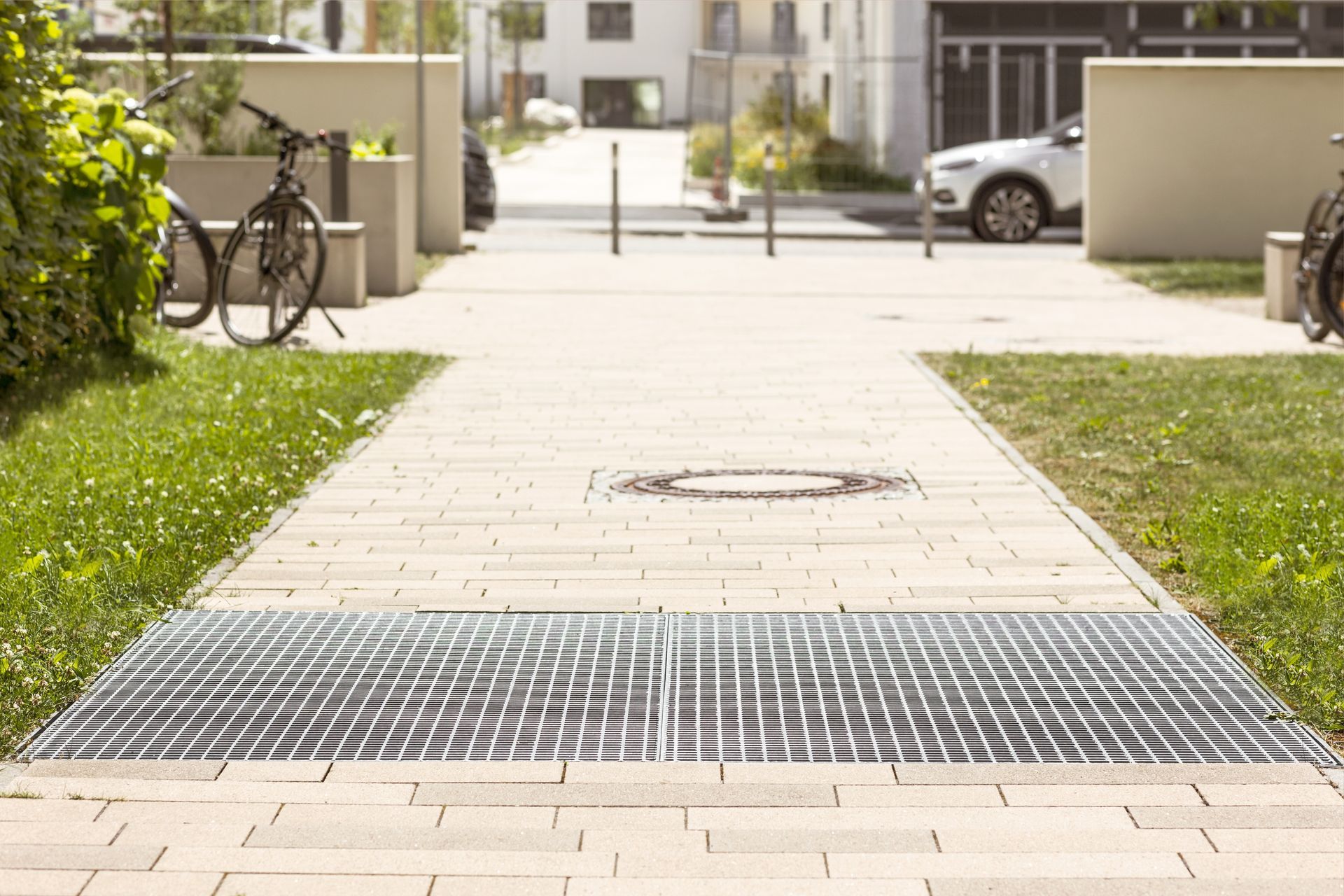 A bicycle is parked on the sidewalk next to a metal grate.