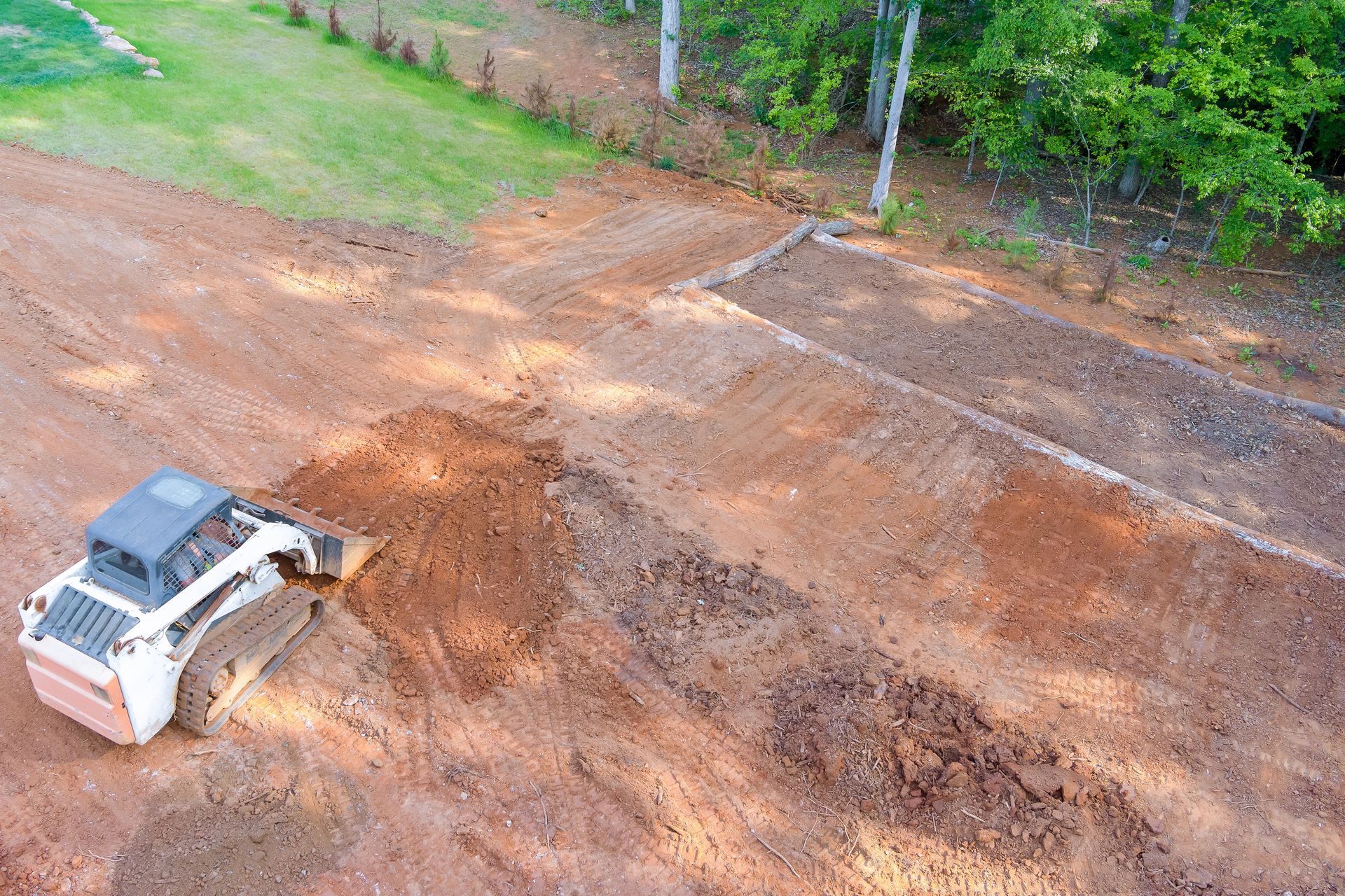 An aerial view of a bulldozer moving dirt on a dirt road.