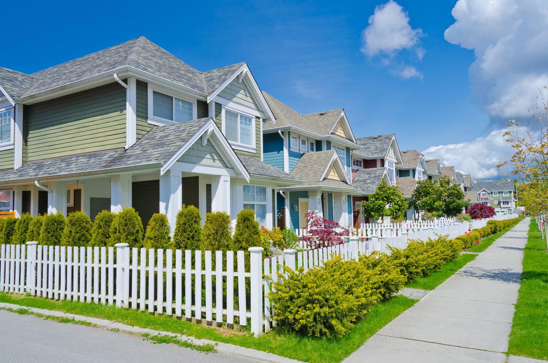 A row of houses with a white picket fence in front of them