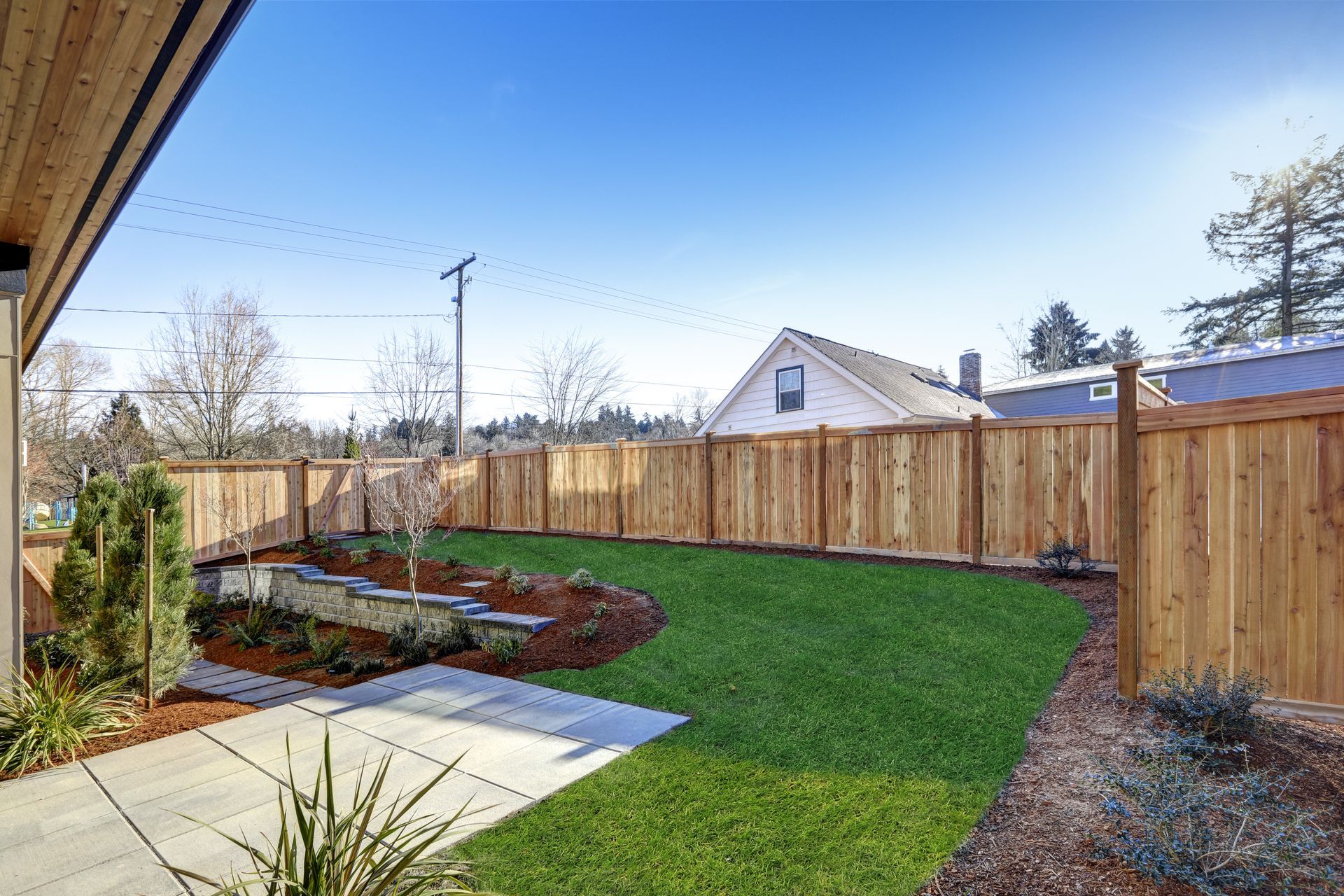 A backyard with a wooden fence and a lush green lawn.