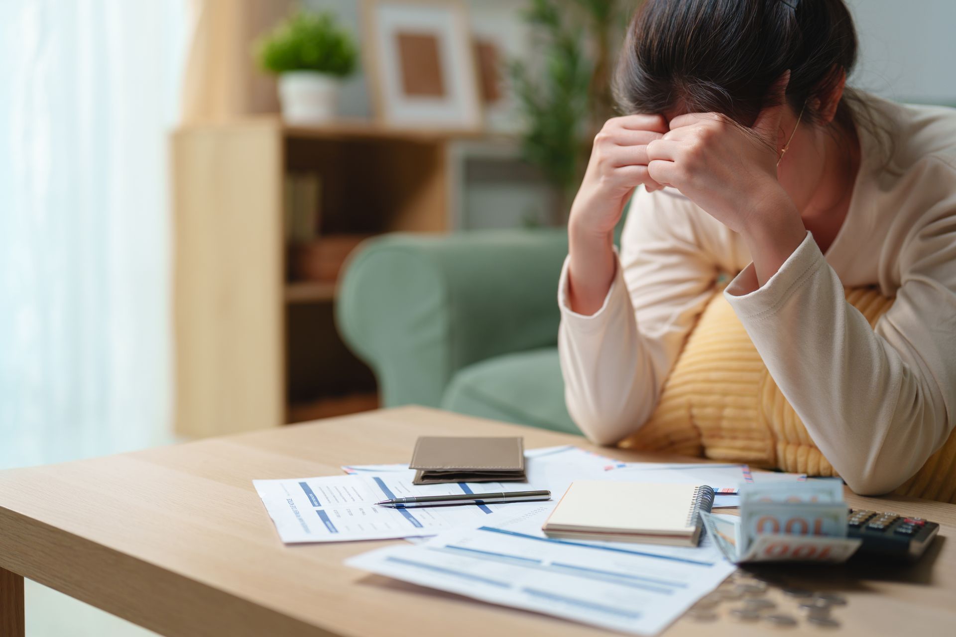 Stressed woman reviewing bills and financial documents at home
