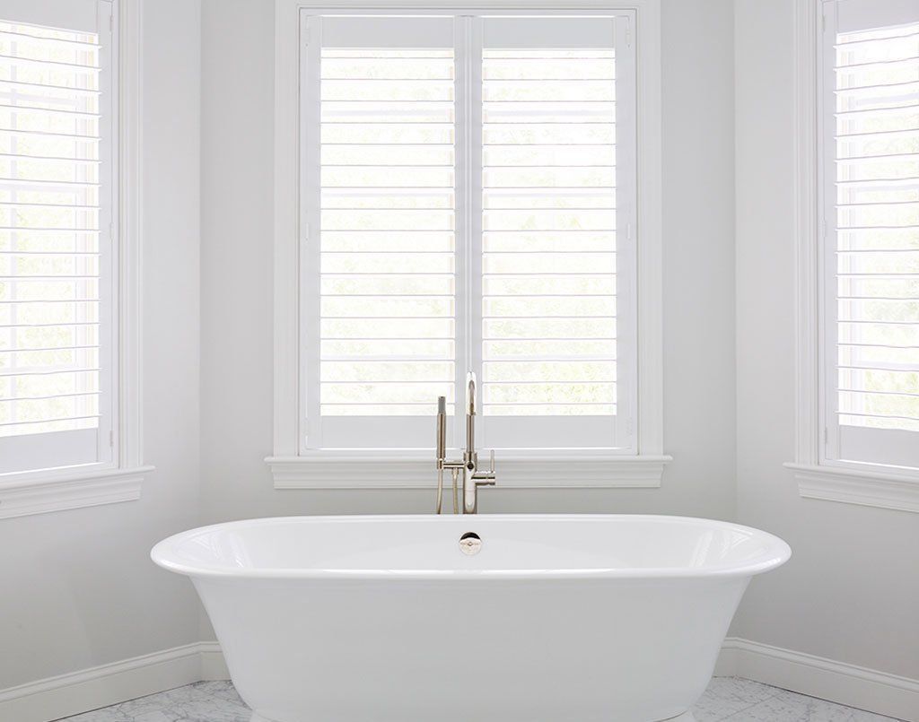 A White Bathtub Is Sitting in A Bathroom Next to Two Windows — Creative Curtains & Blinds In Tweed Heads South, NSW