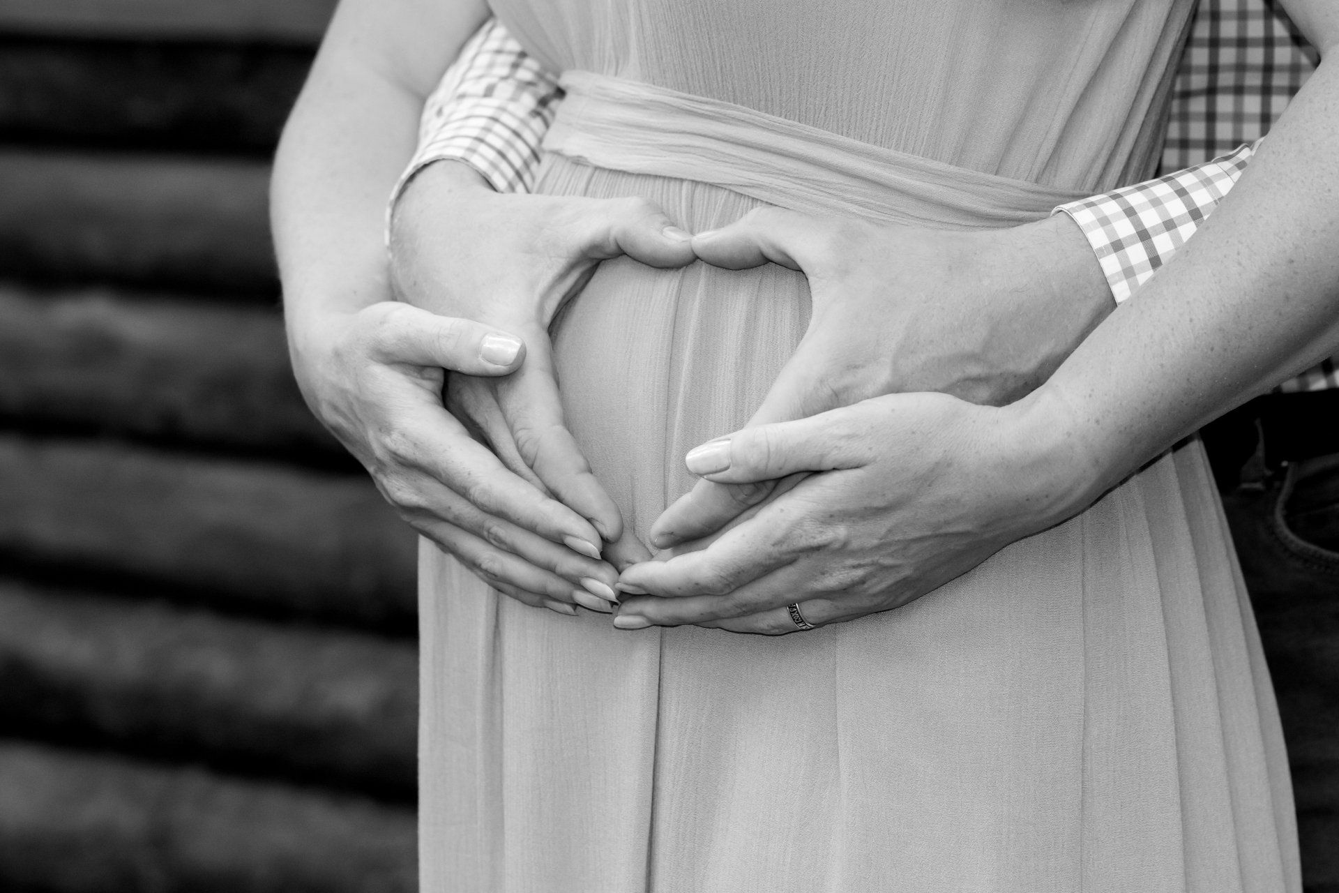 Pregnant woman holding her belly with her hands in the shape of a heart