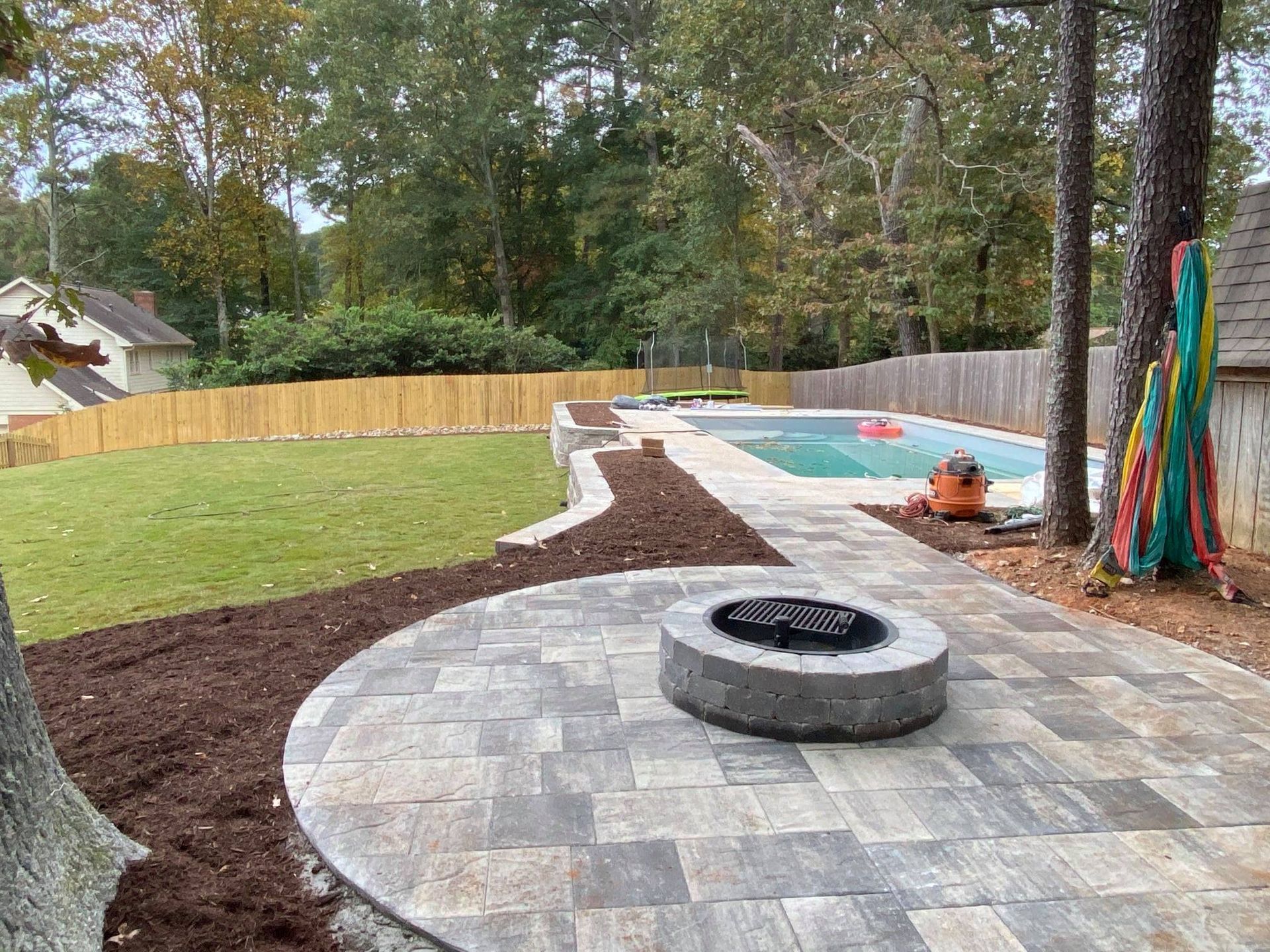 Backyard patio with circular fire pit, paver seating area, and landscaped mulch beds