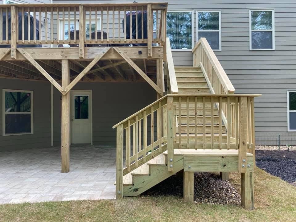 Back deck with ramp leading to a raised patio on a tan house.