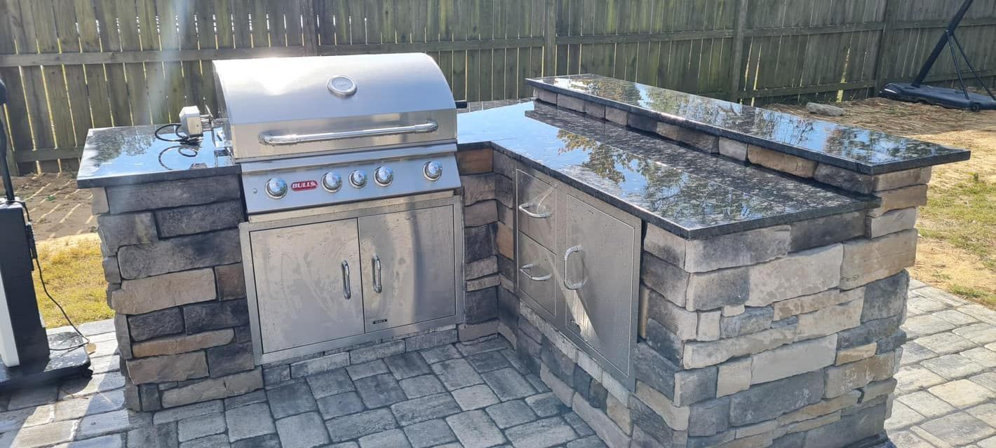 Outdoor brick barbecue grill with stainless steel lid and stone side counters on a patio