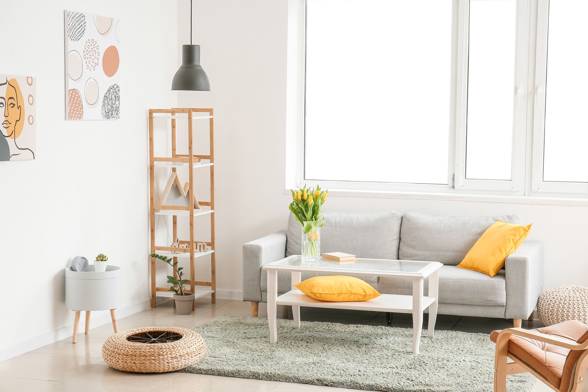Living room with gray sofa, yellow pillows, white table, rug, and art.