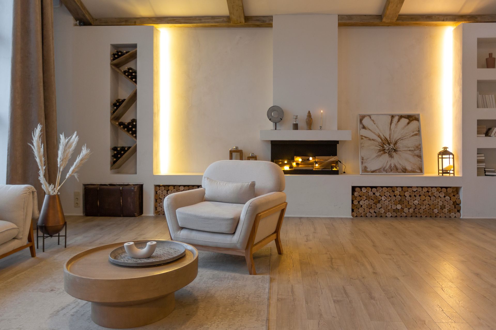 Cozy living room with fireplace, white walls, wood floors, neutral furniture, and warm lighting.
