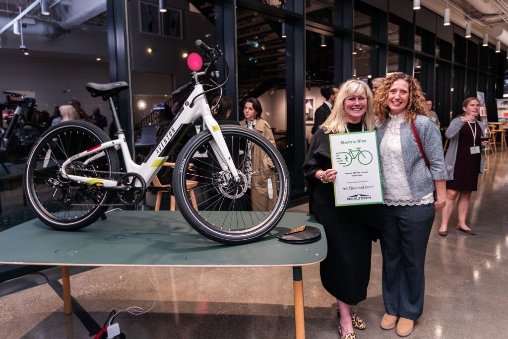 Two women are standing next to a bicycle on a table.