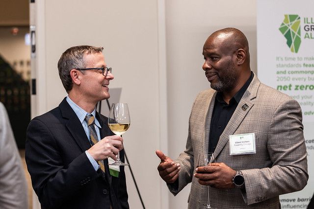 Two men are talking to each other while holding wine glasses.
