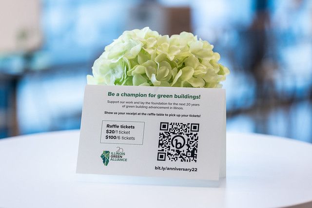 A card with a qr code on it is sitting on a table next to a vase of flowers.