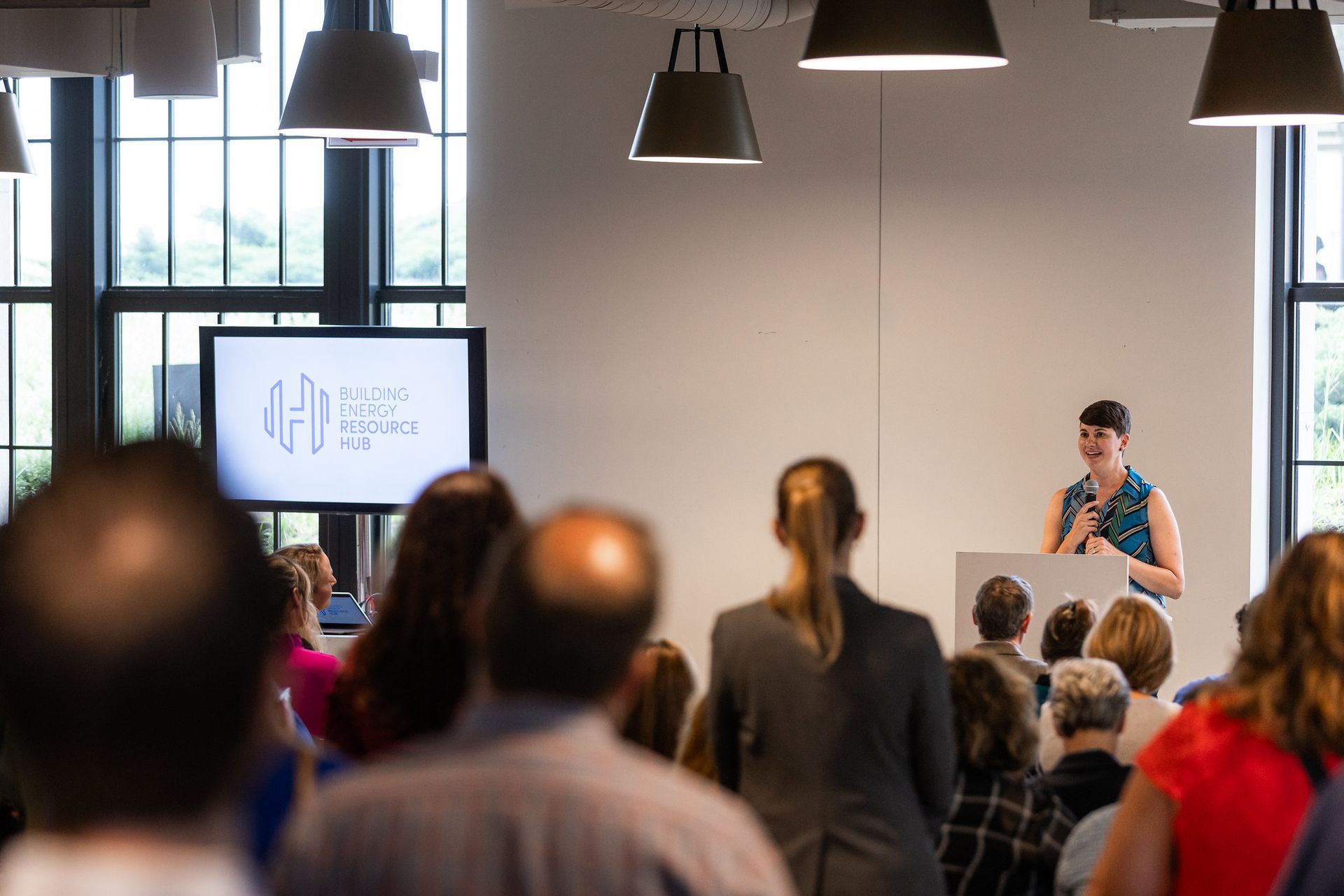 A woman is standing at a podium giving a presentation to a group of people.