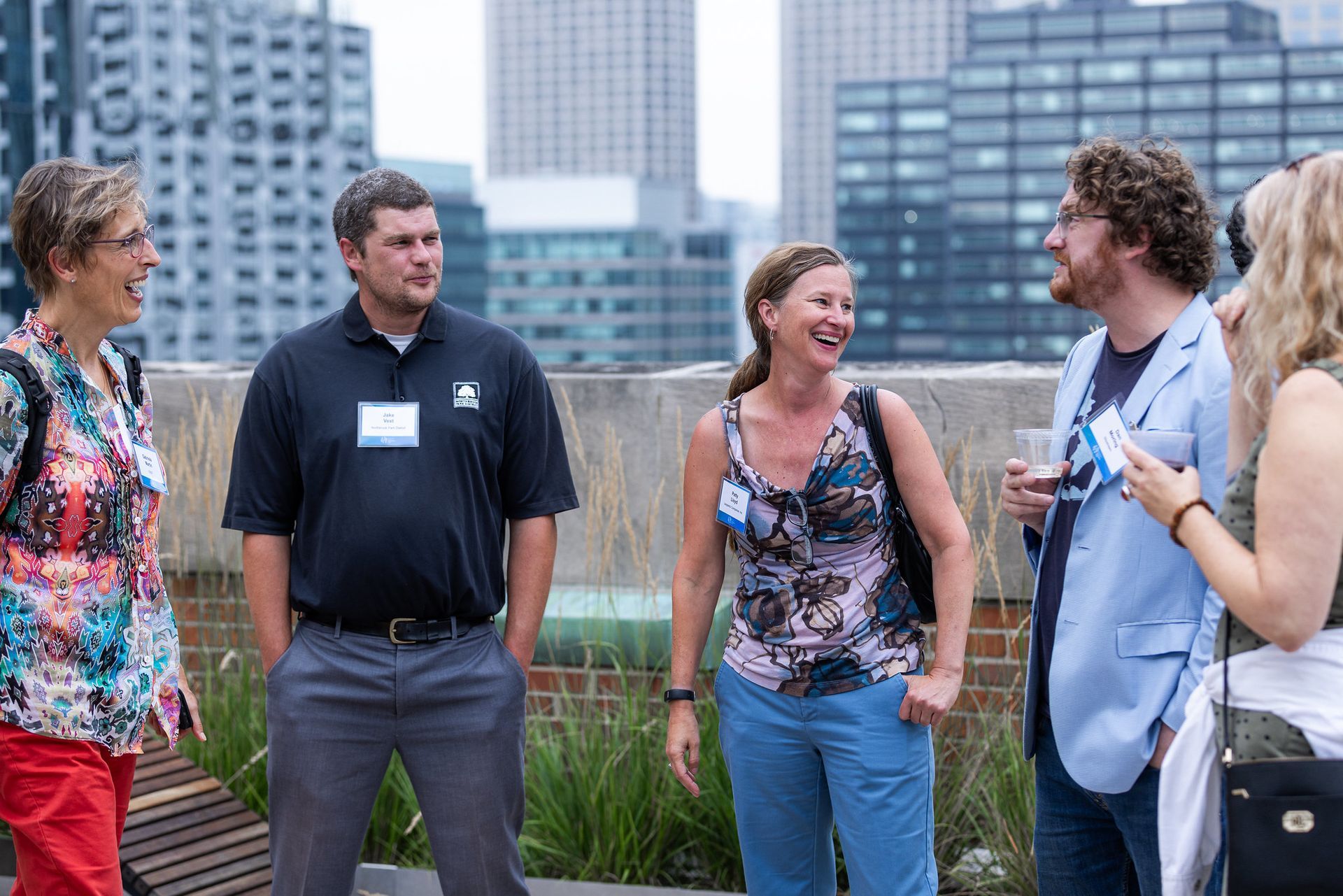 A group of people are standing on a rooftop talking to each other.