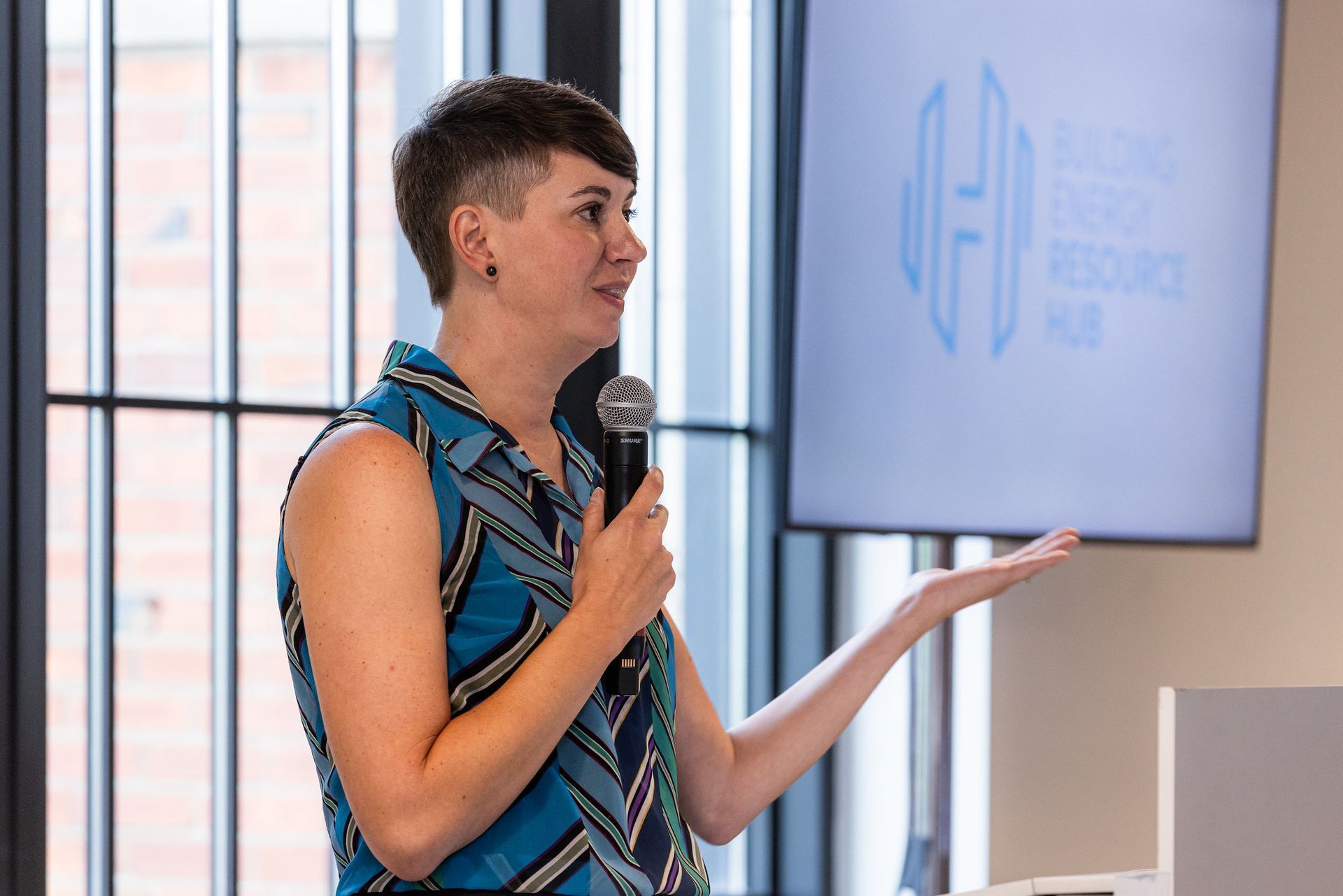 A woman is holding a microphone and giving a presentation.