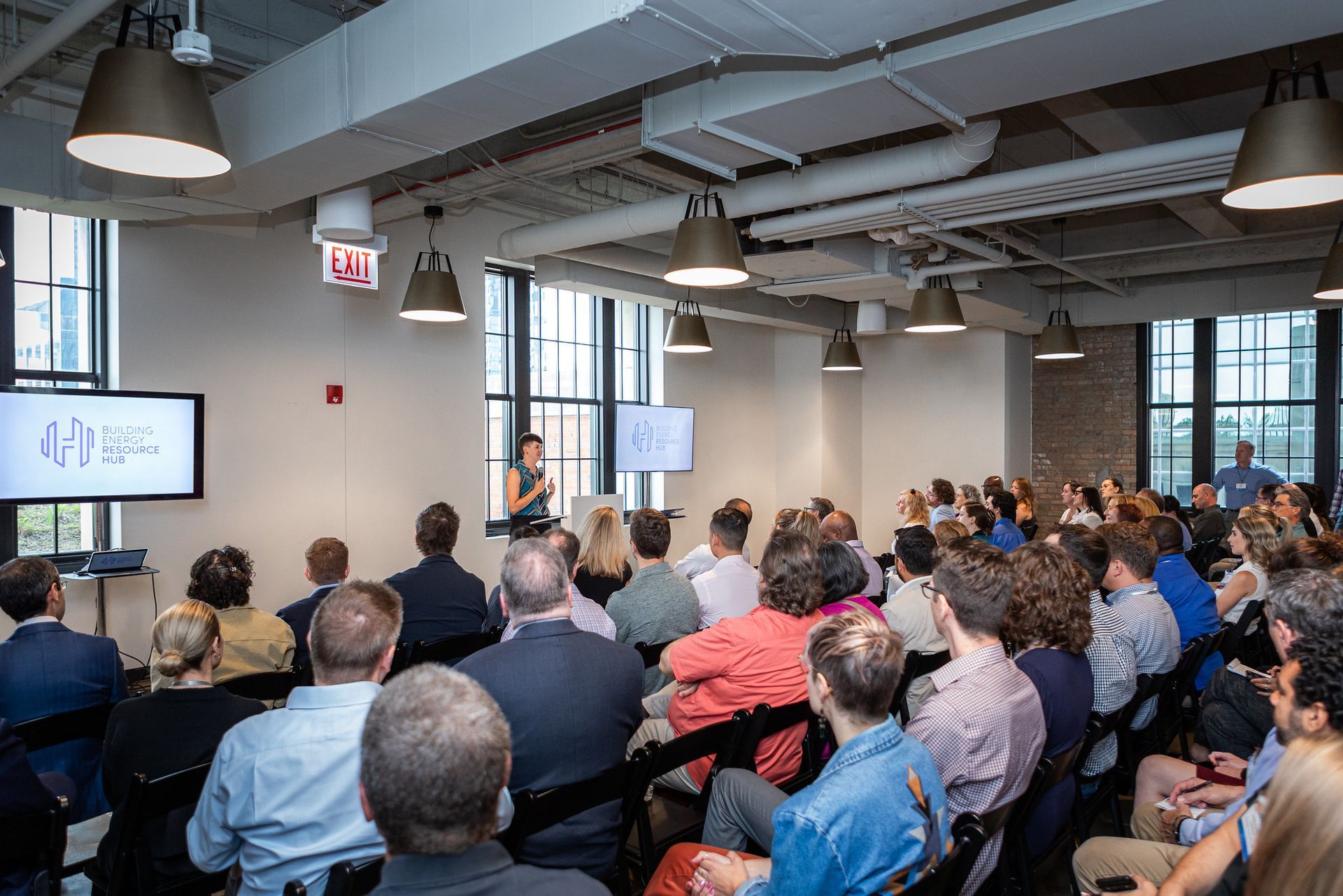 A woman is giving a presentation to a large group of people in a large room.