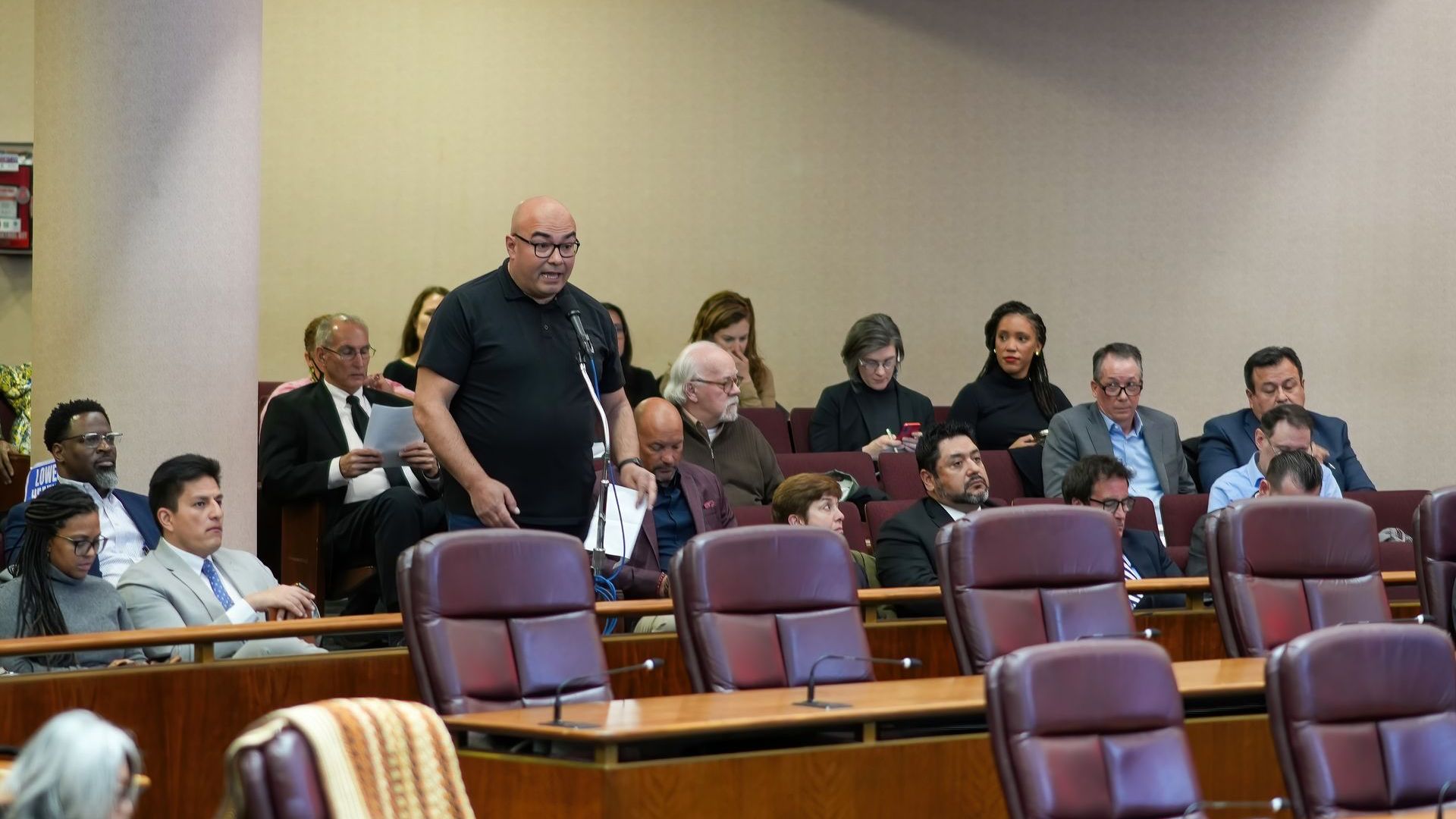 A man is standing in front of a group of people in a room.