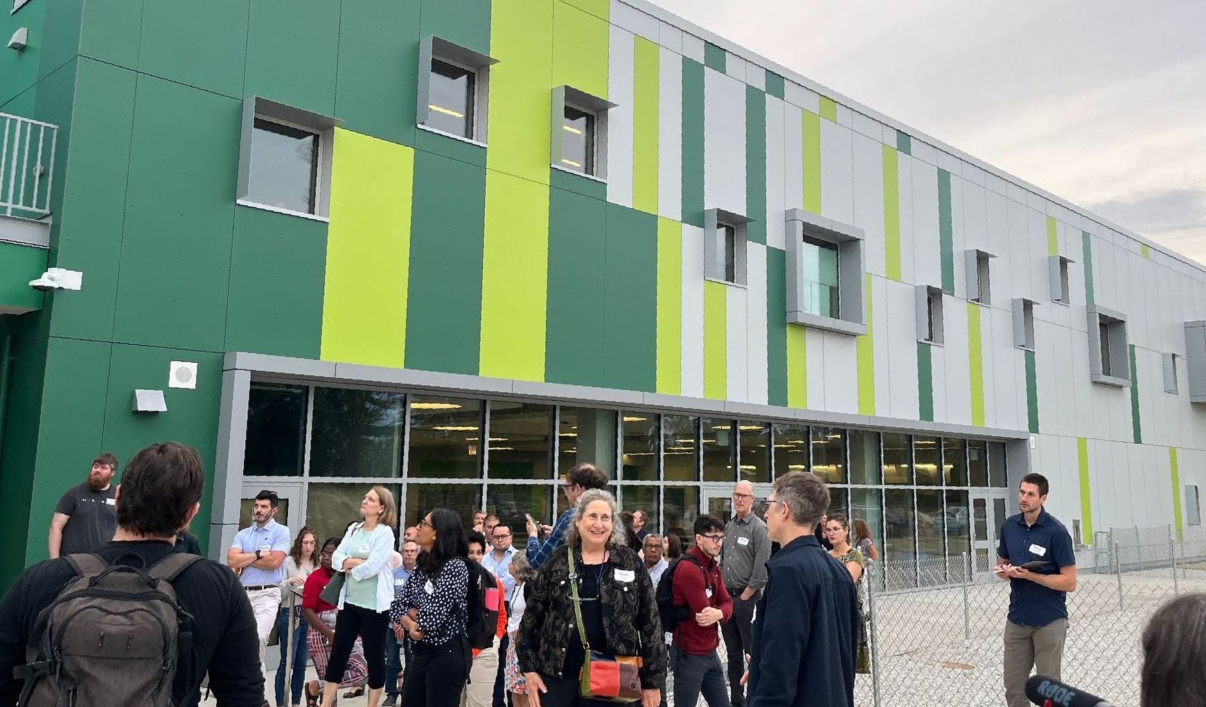 A group of people are standing in front of a green and white building.