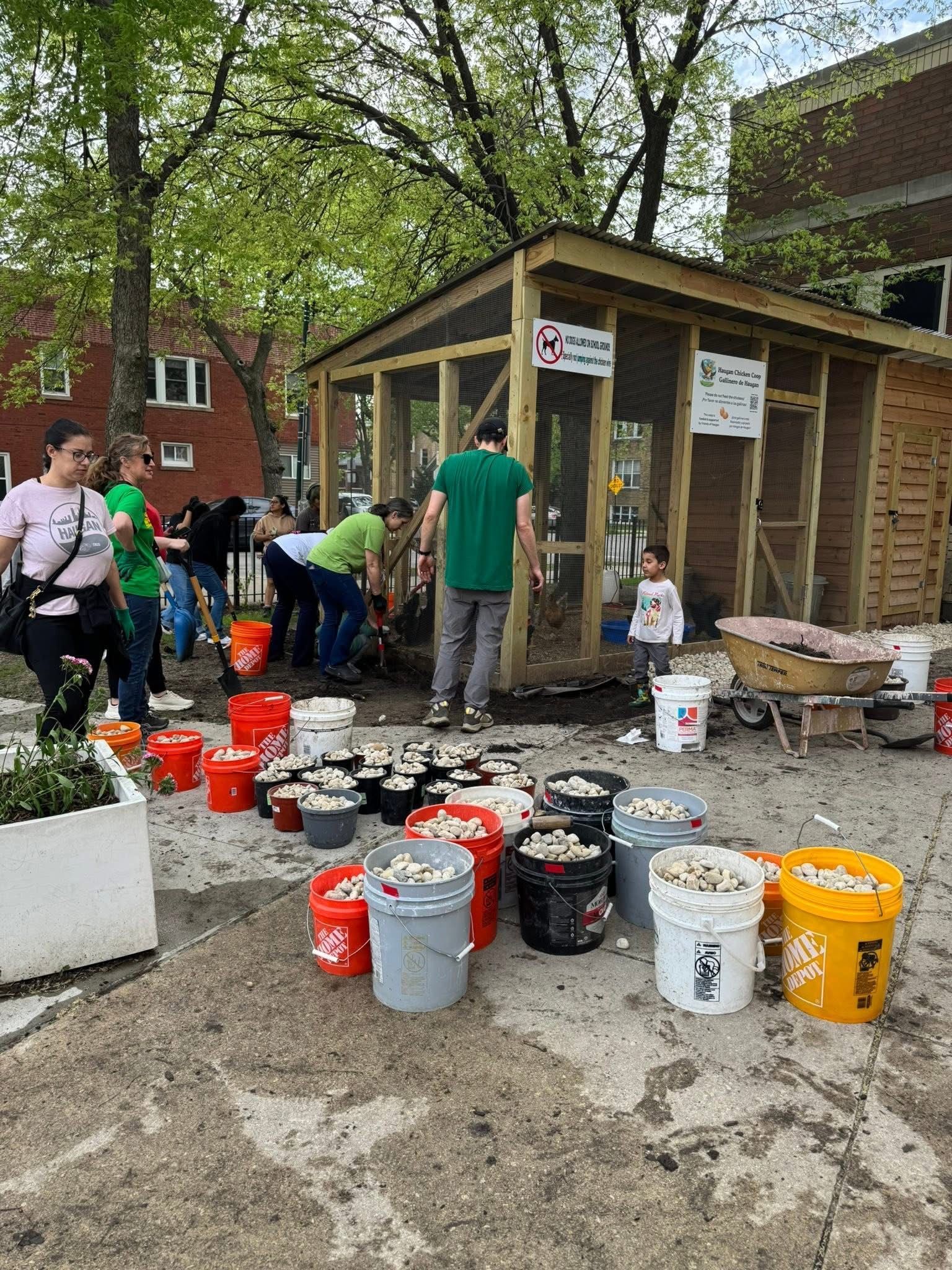 Volunteers outside placing drainage rocks around a chicken coop.