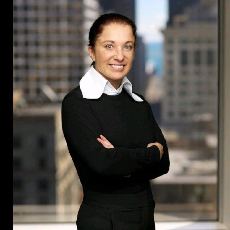 A woman in a black sweater is smiling with her arms crossed