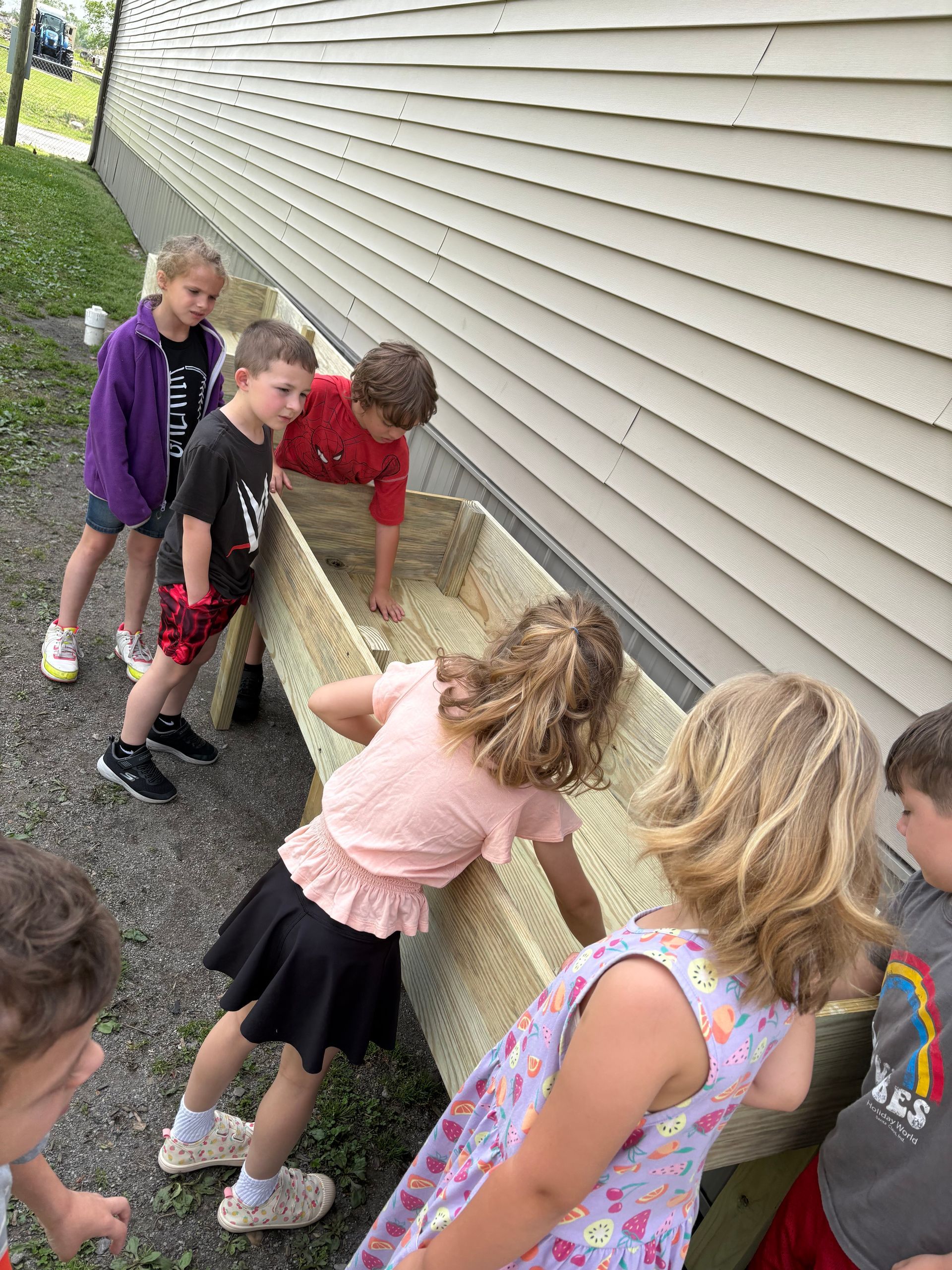 Students feeling a wooden planter with their hands; preparing to add plants.