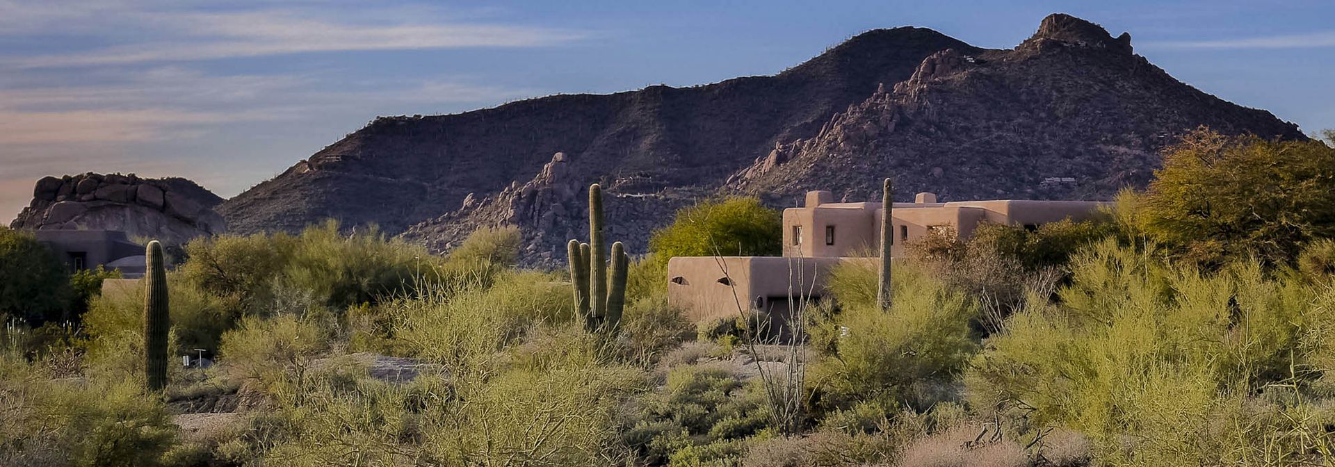 Desert landscape with mountains, vegetation, and a building.