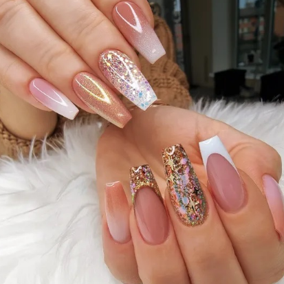 Nahaufnahme einer Hand mit langen, sargförmigen, manikürten Nägeln in verschiedenen Farben, darunter Nude, Glitzer und French Tips.
