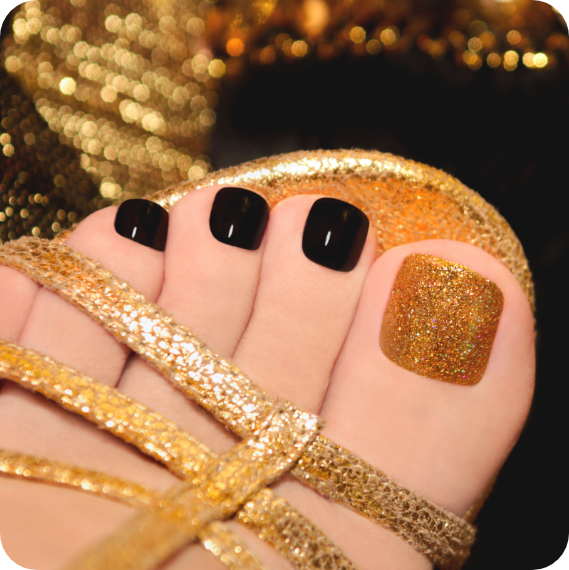 Fuß mit schwarz-goldenen Zehennägeln in einer goldenen Sandale.