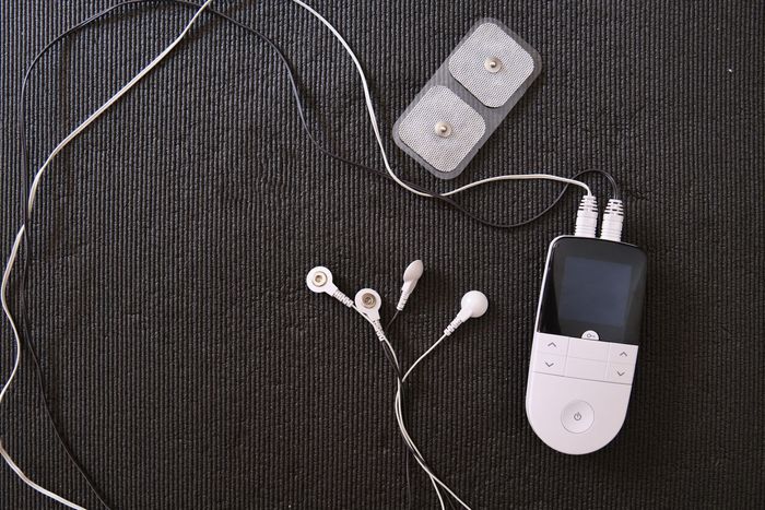 TENS unit with white pads and white and black wires on a black background