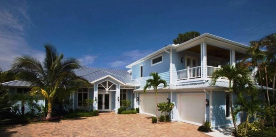 A large blue and white house with palm trees in front of it.