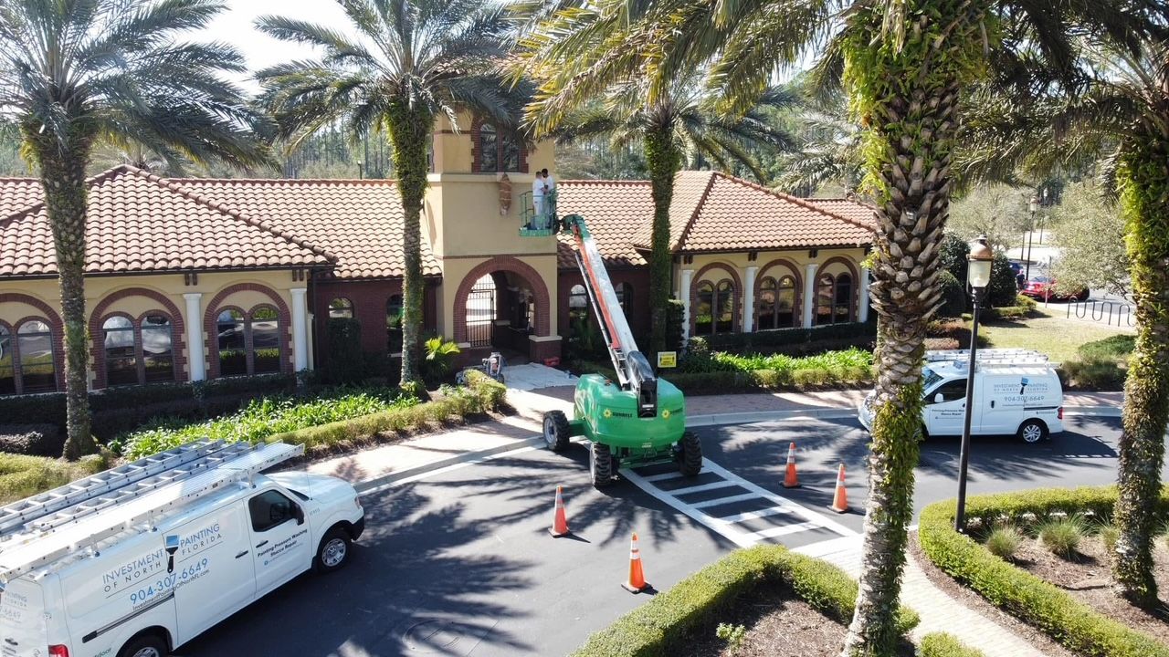 A white van is parked in front of a building with palm trees.