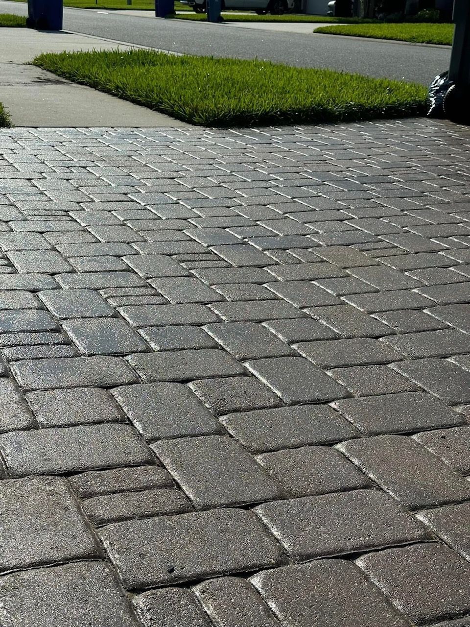 A close up of a brick driveway with grass on the side of the road.